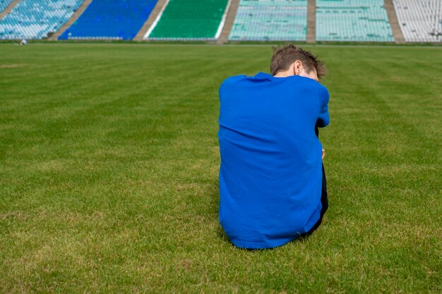 Vermoeide mannelijke atleet sportman ontspannen op het grasveld na trainingen