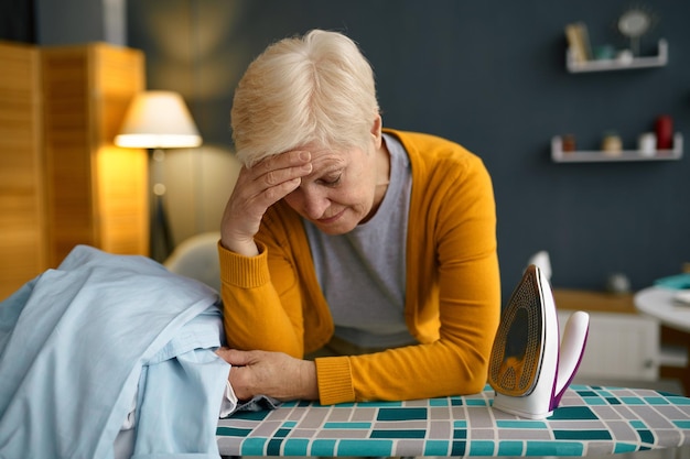 Vermoeide oude vrouw voorkant van strijkplank