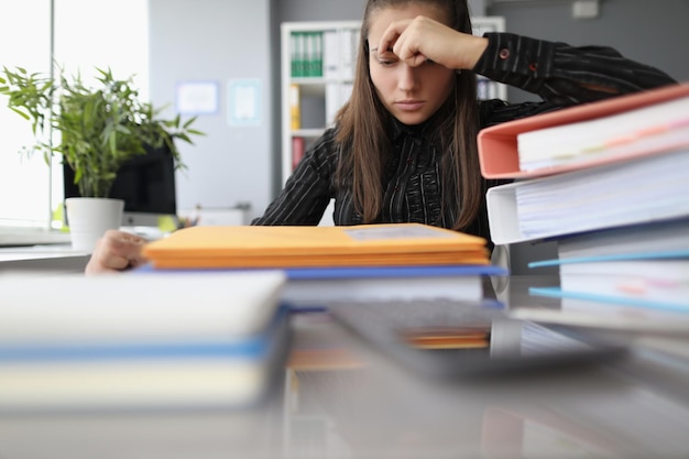 Vermoeide overwerkte vrouw met hopeloze blik op stapel documenten