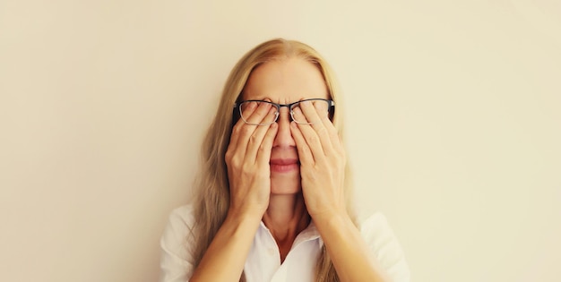 Vermoeide overwerkte vrouwelijke werknemer die haar ogen wrijft en lijdt aan het droge oogsyndroom.