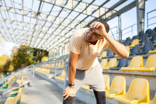 Vermoeide Spaanse atleet boog zich voorover en ademde na het joggen van een man die sport deed op een zonnige dag met