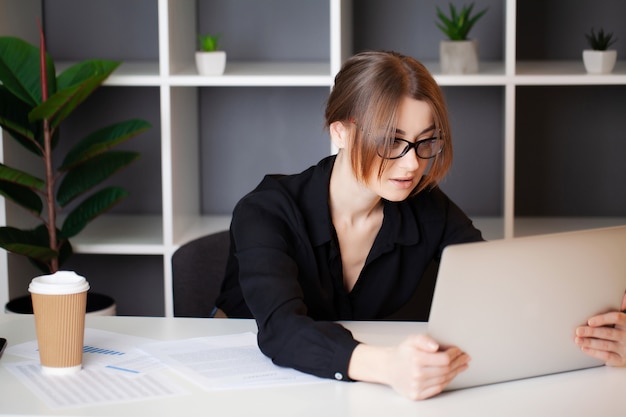 Vermoeide vrouw die bij de computer in het bureau werkt