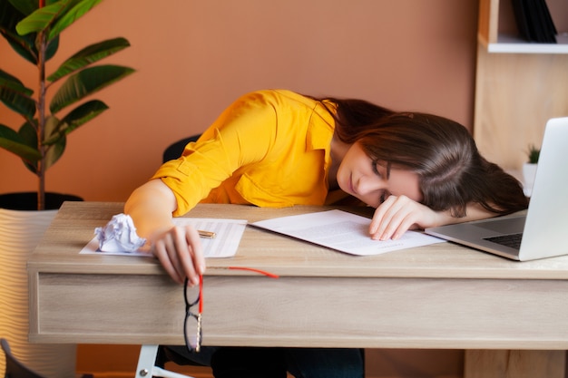 Vermoeide vrouw die bij laptop in het bureau werkt