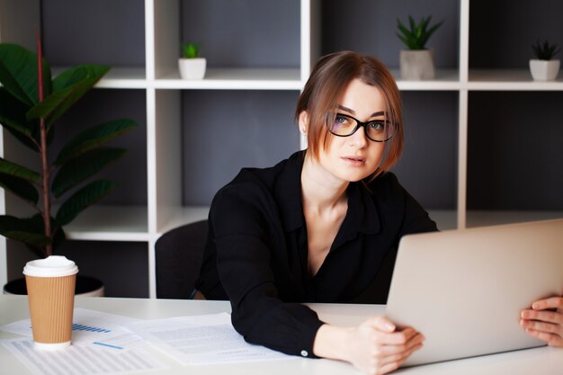 Vermoeide vrouw die bij laptop werkt