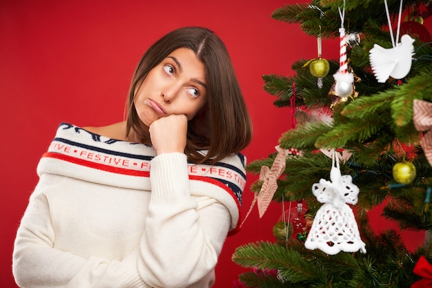 vermoeide vrouw kerstboom versieren op rode achtergrond decorating