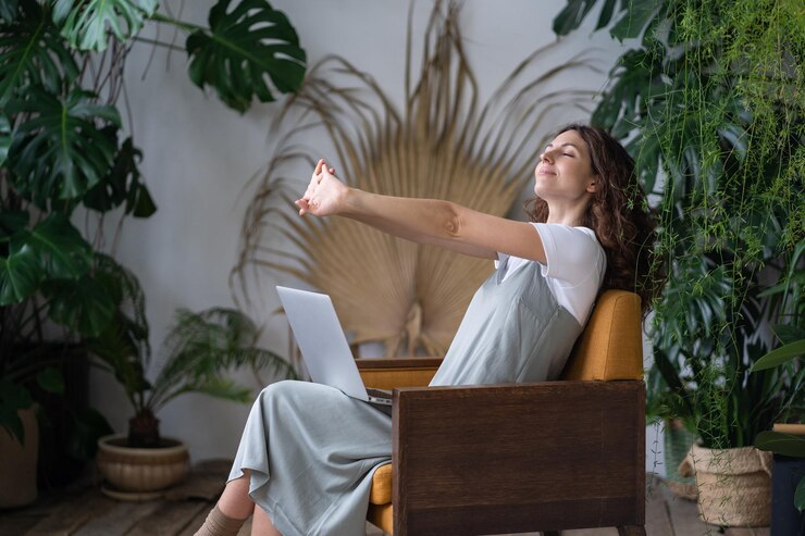 Foto vermoeide vrouwelijke freelancer die zijn armen uitrekt terwijl hij aan het werk is op een laptop in een gezellige tuin