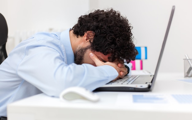 Vermoeide zakenman die in zijn bureau werkt