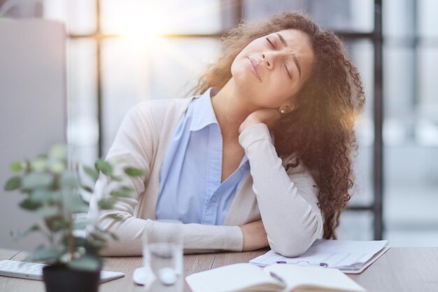 Vermoeide zakenvrouw die aan een bureau zit en werkt