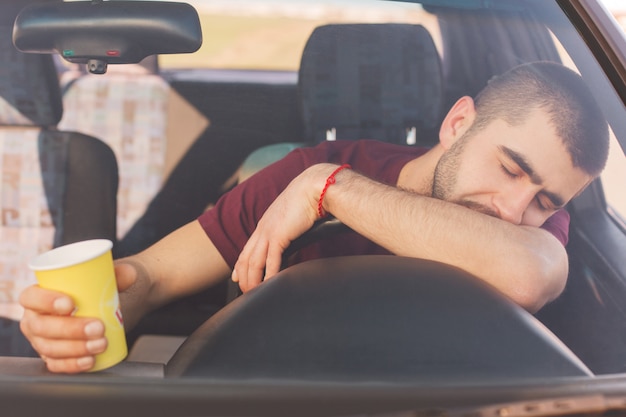 Vermoeidheid overwerkt moe mannelijke bestuurder heeft een lange reis in de auto