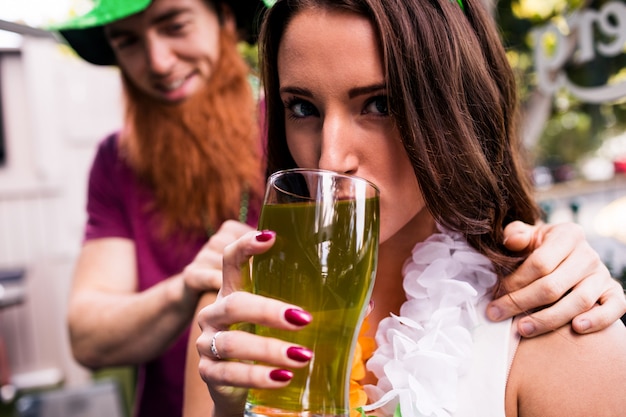 Vermomde vrouw die een groene pint houdt