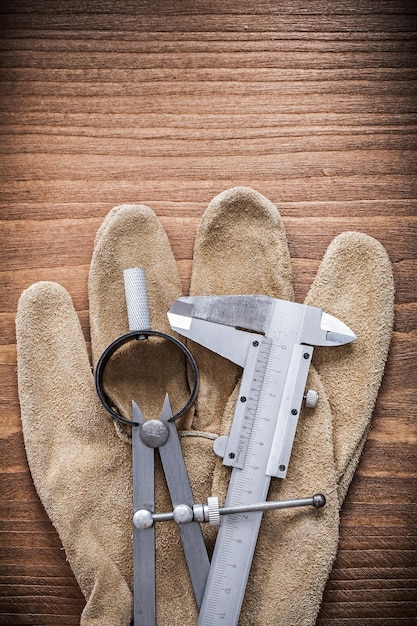 Vernier scale divider leather safety gloves on wooden board