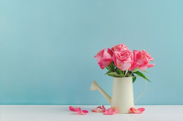 Foto vernietigd nam bloemen bij gieter op witte en blauwe houten achtergrond toe