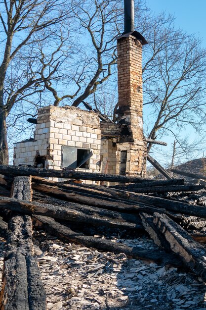 Vernietigde huizen als gevolg van een brand in Rusland Een oude bakstenen rustieke kachel bedekt met as en gedeeltelijk verwoest na een zware brand in een houten huis Natuurramp