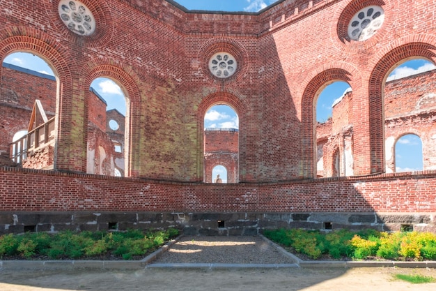 Vernietigde rode bakstenen muren. Raamopeningen van een verlaten kerk. De oude heilige plaats is in puin.