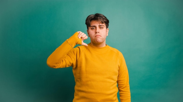 Foto verontwaardigde jonge man met duim naar beneden in de groene studio.