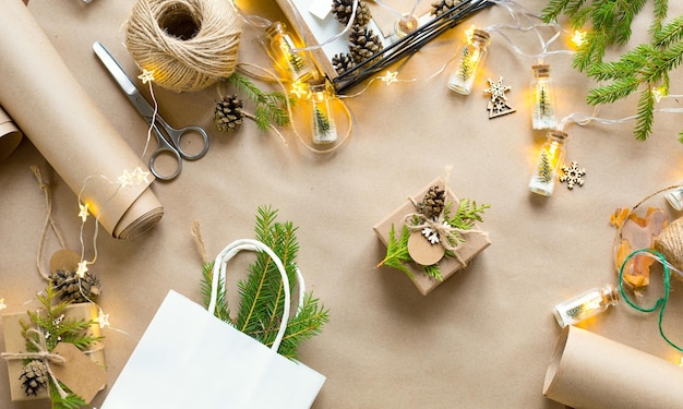 Verpak een cadeau voor kerstmis en nieuwjaar in milieuvriendelijke materialen: kraftpapier, levende dennentakken, kegels, touw. tags met mock up, natuurlijk decor, handgemaakt, diy. feestelijke stemming. kerst achtergrond