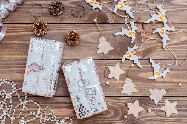 Verpakt in feestelijke verpakking geschenkdozen gebonden met zilveren lint en kerstversiering op een houten tafel. Kerstmis voorbereiden.