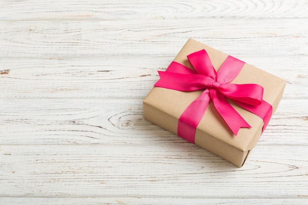 Verpakt kerst- of ander met de hand gemaakt cadeau voor de feestdagen in ambachtelijk papier met gekleurd lint Huidige doosdecoratie van cadeau op tafelblad met kopieerruimte