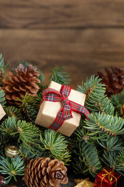 Verpakte geschenkdozen op dennentakken in de buurt van kerstversieringen en dennenappels