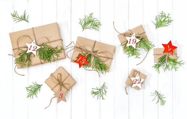 Verpakte geschenken Adventskalender met kerstboom takken decoratie op lichte houten achtergrond. plat leggen