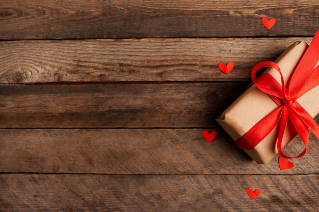 Verpakte vintage geschenkdoos met rood lint boog en harten op donkere houten tafel met kopie ruimte, wenskaart voor valentijnsdag