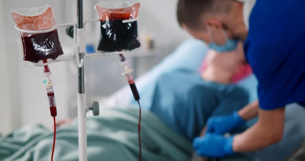 Verpleegkundige die een injectiespuit in de arm van de vrouwelijke patiënt injecteert voor bloedtransfusie