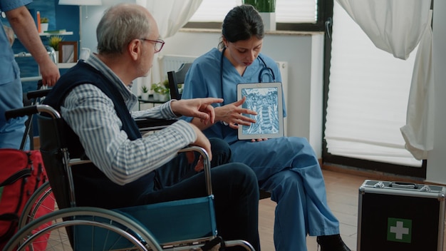 Verpleegkundige legt osteopathie röntgenfoto op tablet uit aan man