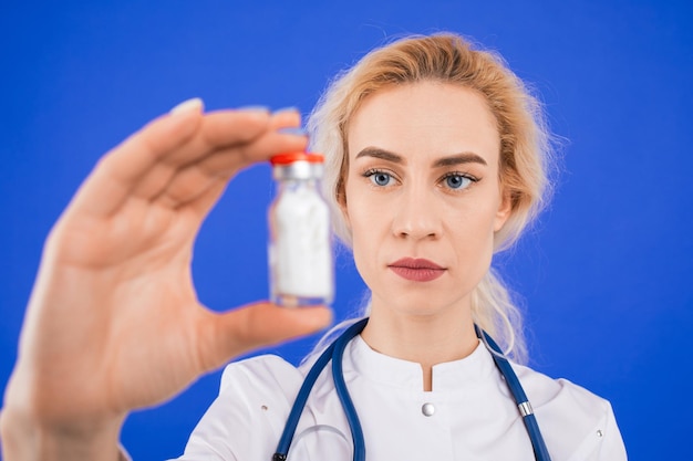 Verpleegkundige met een fles witte medische suspensie op een blauwe achtergrond