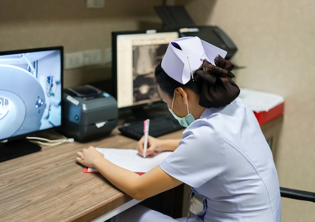 Foto verpleegkundige record vitale teken in medische grafiek op computed tomography werkstation roo