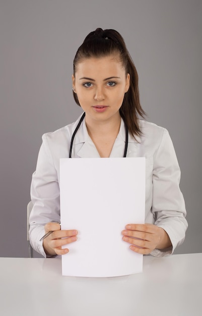 Verpleegkundige zit aan tafel met twee papieren