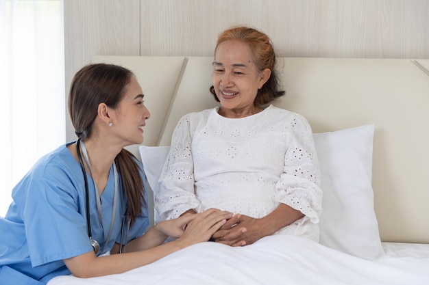 Verpleegkundige zorg patiënt bejaarde senior vrouw praten troost herstel op bed thuis