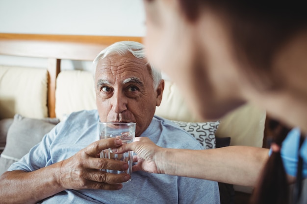 Verpleegster die een glas water geeft aan de hogere mens