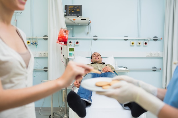 Verpleegster die koekjes geeft aan een patiënt