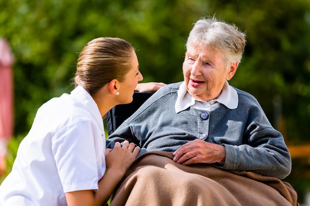 Foto verpleegster hand in hand met senior vrouw in rolstoel