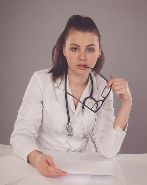 Verpleegster in badjas en bril en stethoscoop bekijkt haar rapport en denkt erover na aan tafel
