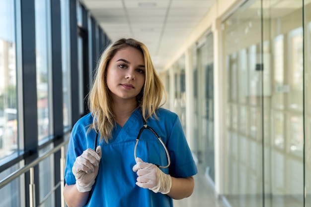 verpleegster in blauw uniform met stetoscoop binnenshuis in moderne kliniek