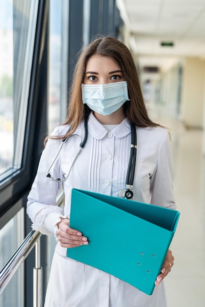 Verpleegster in het blauw met een medisch masker schrijft informatie over de patiënt op