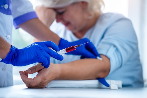 Verpleegster in rubber blauwe medische handschoenen neemt bloedmonster uit een ader voor laboratoriumtest. Medische onderzoek