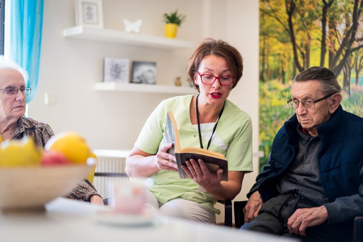 Verpleegster leesboek aan oudere groep mensen