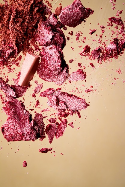 Verpletterde cosmetica minerale organische oogschaduw blush en cosmetische poeder geïsoleerd op gouden achtergrond ...