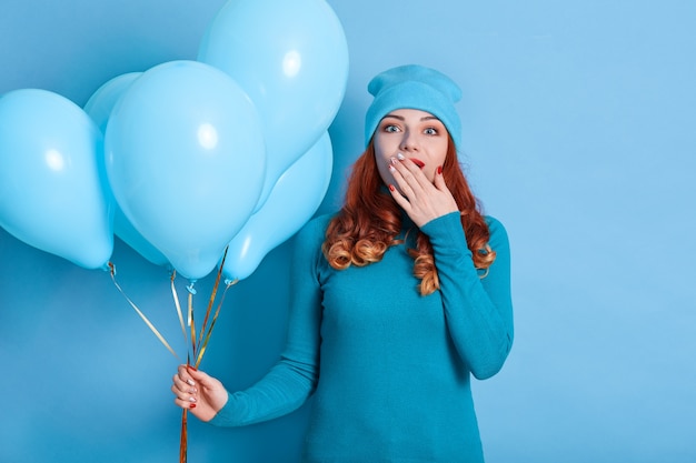 Verrast dame die ballonnen vasthoudt en de mond bedekt met de hand