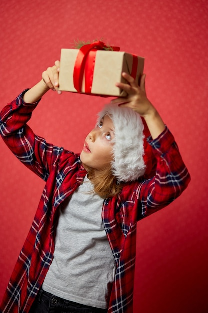 Verrast en positief meisje in kerstmuts met kerstcadeau