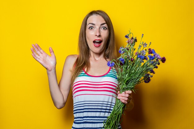 Verrast geschokt jonge vrouw in gestreepte jurk met wilde bloemen