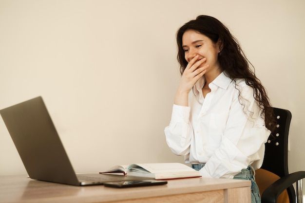 Verrast meisje dat geniet van een vriendelijk videogesprek op een laptopcomputer die een webcamera gebruikt om videocommunicatie met collega's thuis te communiceren