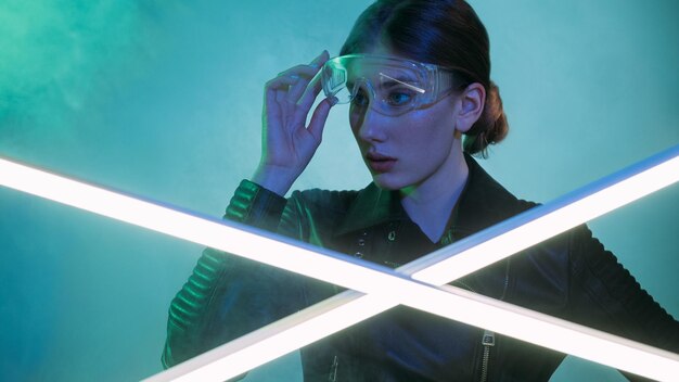 Verrast meisje Futuristisch portret Wetenschappelijk experiment technologie Nieuwsgierige verwarde vrouw opstijgen beschermende bril in blauw groen neon licht kleur rook Led-lamp gloed