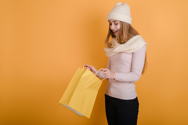 Verrast meisje kijkt in een papieren zak op een gele achtergrond