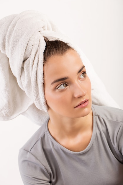 Verrast meisje met een handdoek op haar hoofd op een witte achtergrond