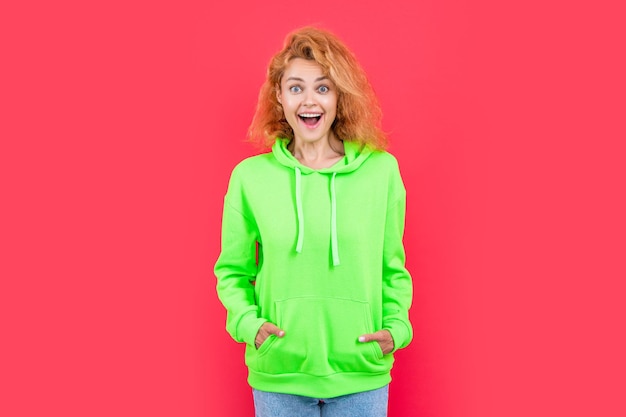 verrast roodharige stijlvolle vrouw op kleur achtergrond stijlvolle vrouw geïsoleerd op rode achtergrond stijlvolle vrouw op studio foto van stijlvolle vrouw in capuchon