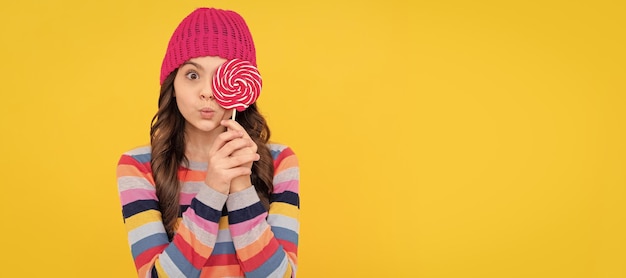 Foto verrast tienermeisje houdt lolly lolly dame hipster kind met kleurrijke lolly suiker snoep tiener kind met snoep poster banner koptekst kopie ruimte