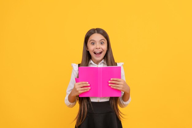 Verrast tienermeisje in schooluniform leesboek, verbazing.